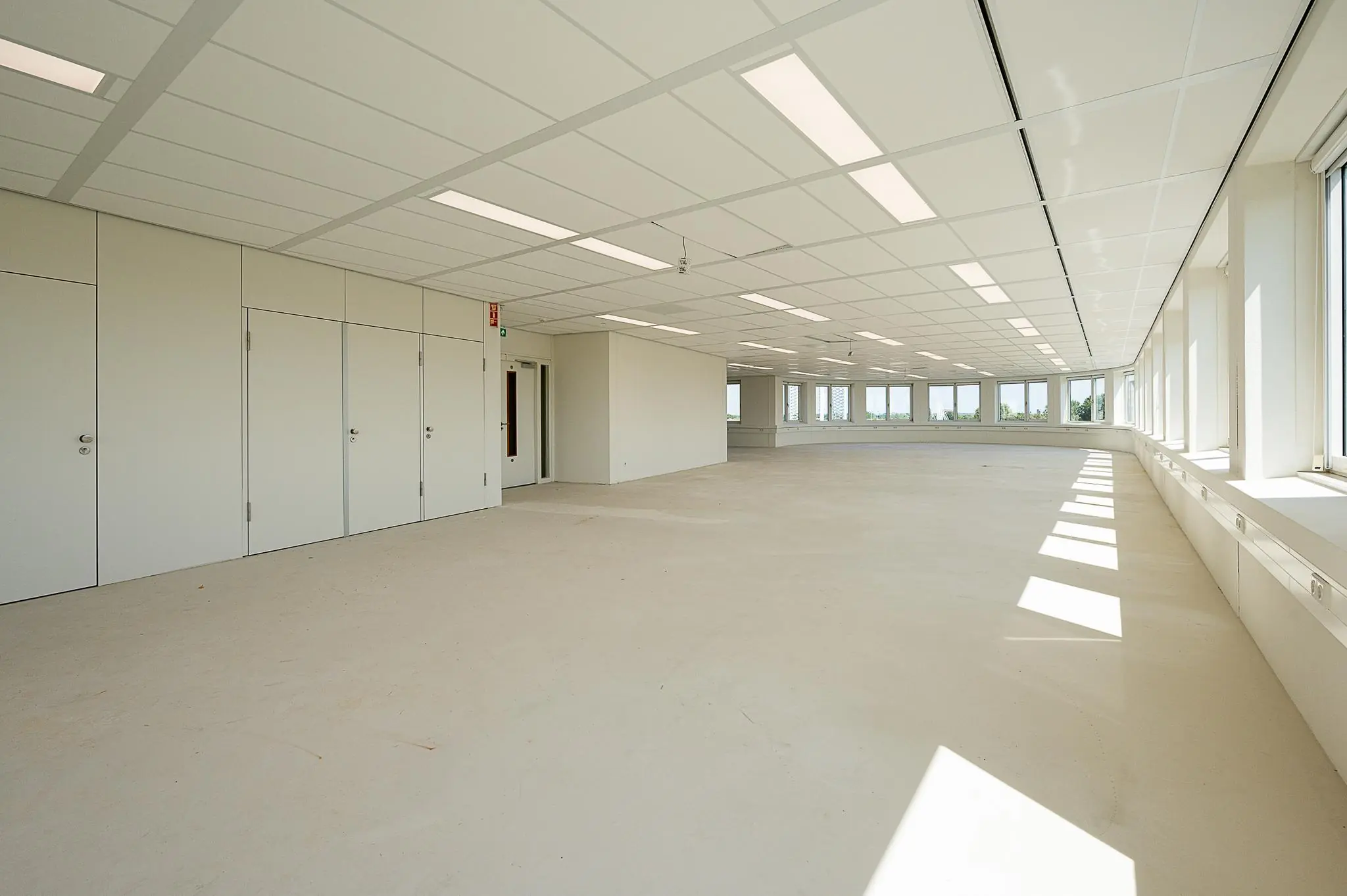 Lichte, lege kantoorruimte aan de Watermanweg met grote ramen en systeemplafond.