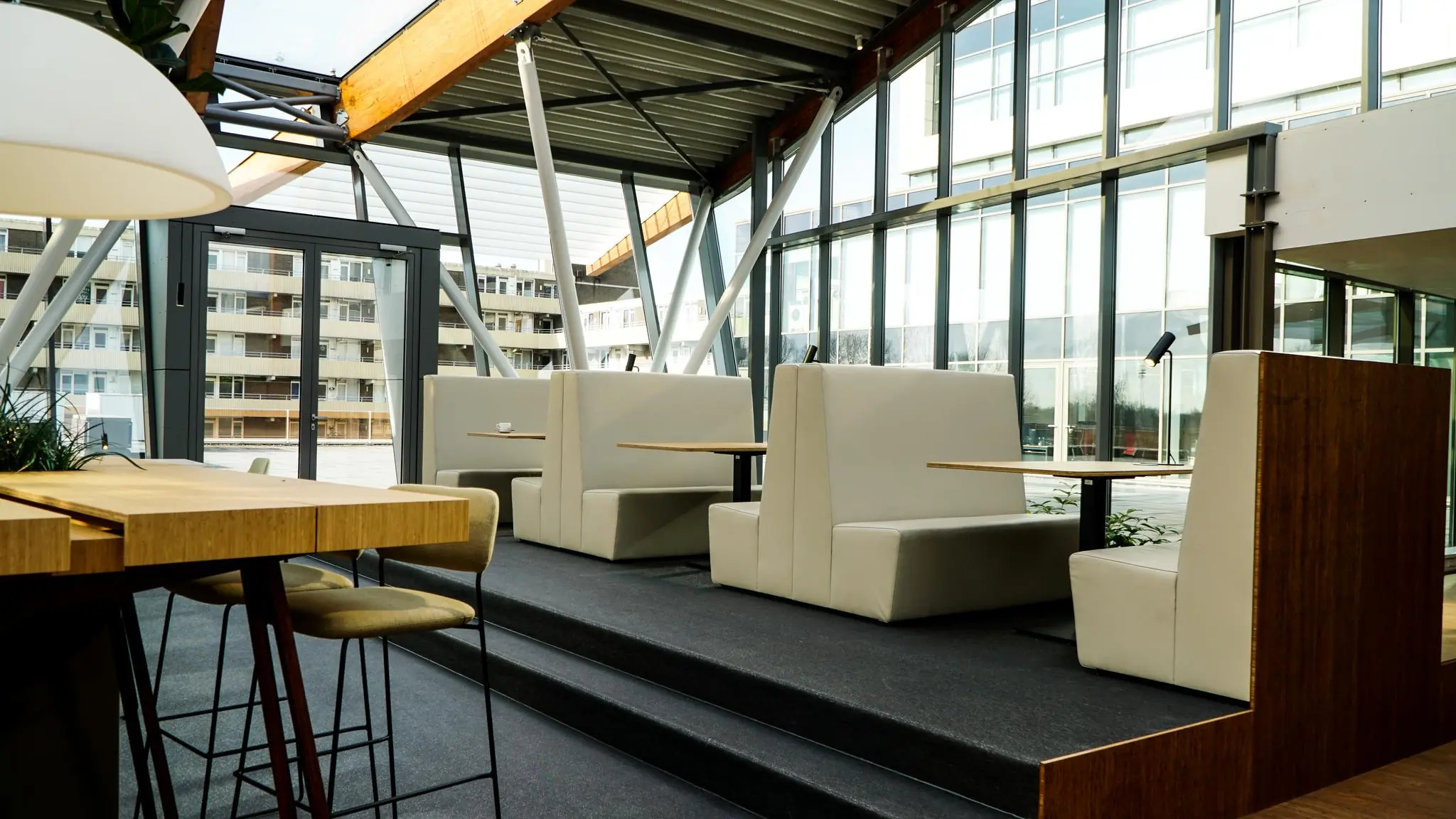 Moderne vergaderruimte met hoge plafonds, glazen wanden en beige zithoeken in gebouw Bisonspoor.