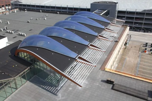 Luchtfoto van het Bisonspoor winkelcentrum met opvallende gebogen dakconstructie met blauwe lichtkoepels.