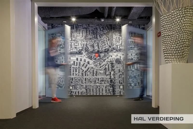 Halverdieping met openzwaaiende deuren en een muur met een luchtfoto van Huizermaatweg, gemarkeerd met een rode locatiepin.