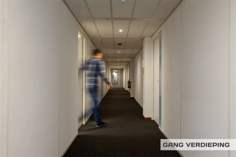 Gang op de verdieping van een kantoorpand aan de Huizermaatweg met een persoon die voorbijloopt.
