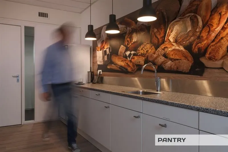 Moderne pantry met witte keukenkastjes, een broodthema-muurschildering en hanglampen boven het aanrecht.