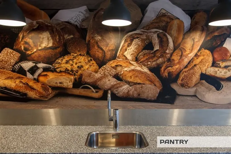 Pantry met een spoelbak en een grote muurfoto van diverse soorten ambachtelijk brood.