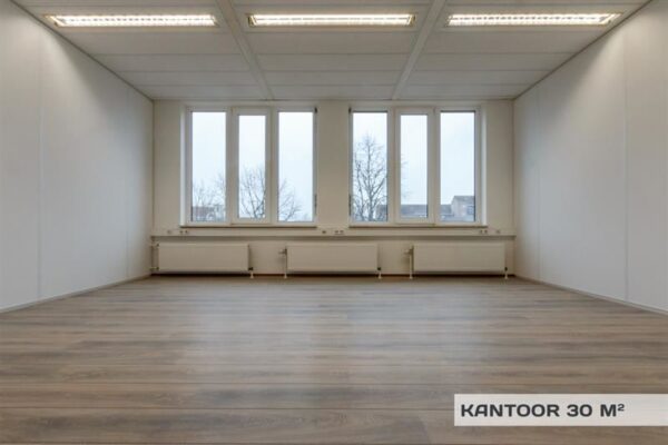 Leeg kantoor van 30 m² met houten vloer, witte wanden en grote ramen aan de Huizermaatweg.