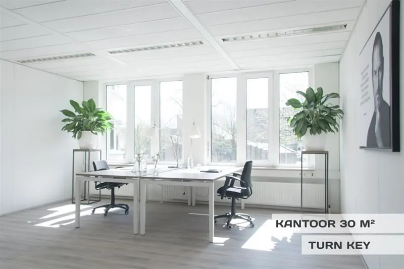 Licht en modern kantoor van 30 m² aan de Huizermaatweg met twee bureaus, grote ramen en groene planten.