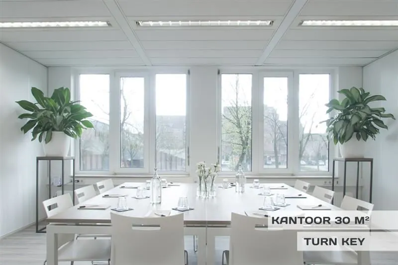 Licht en modern ingericht kantoor van 30 m² aan de Huizermaatweg, met vergadertafel, witte stoelen en grote ramen.
