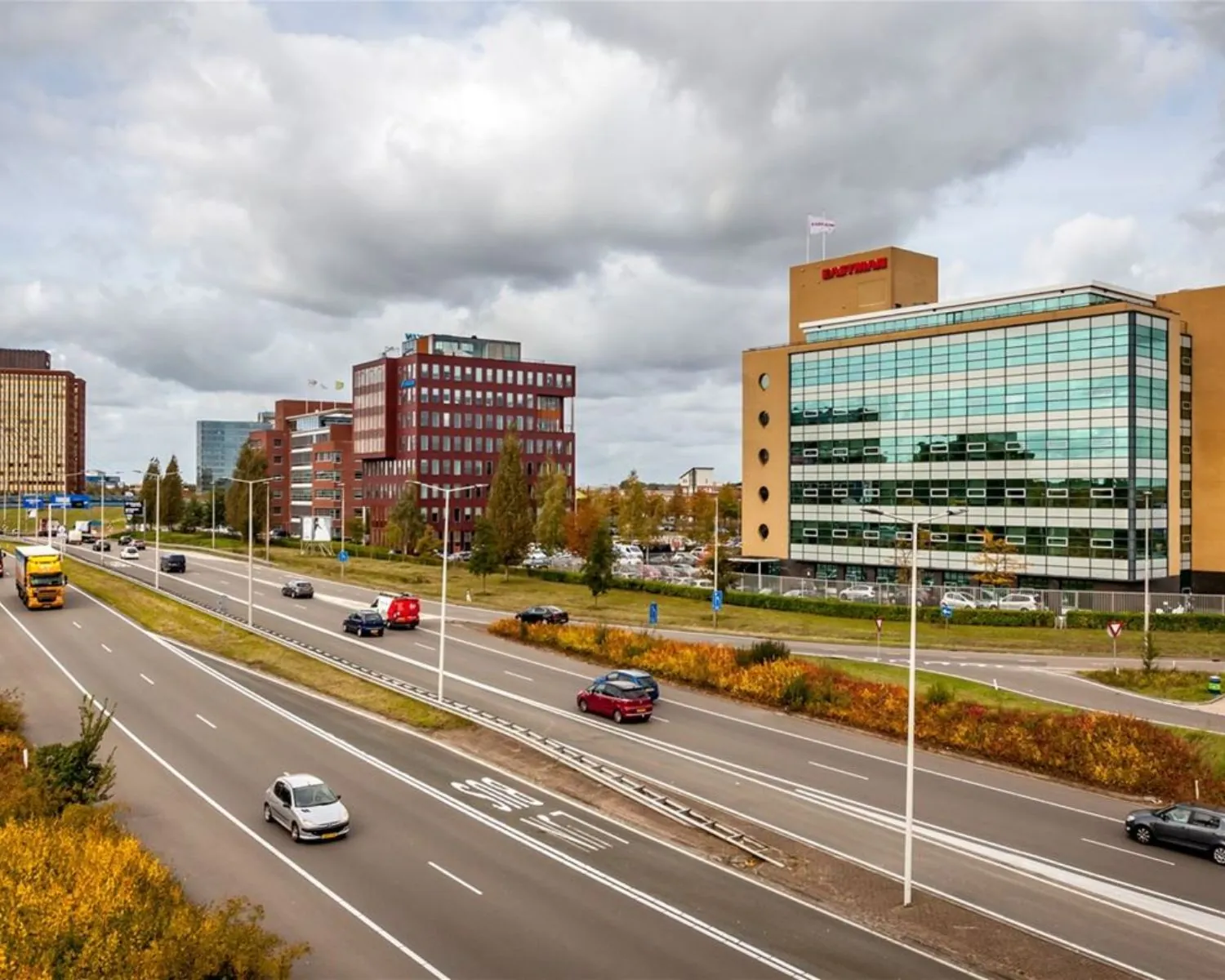 Kantoorgebouwen langs een drukke snelweg met het opvallende glazen pand van het bedrijf Batenburg.