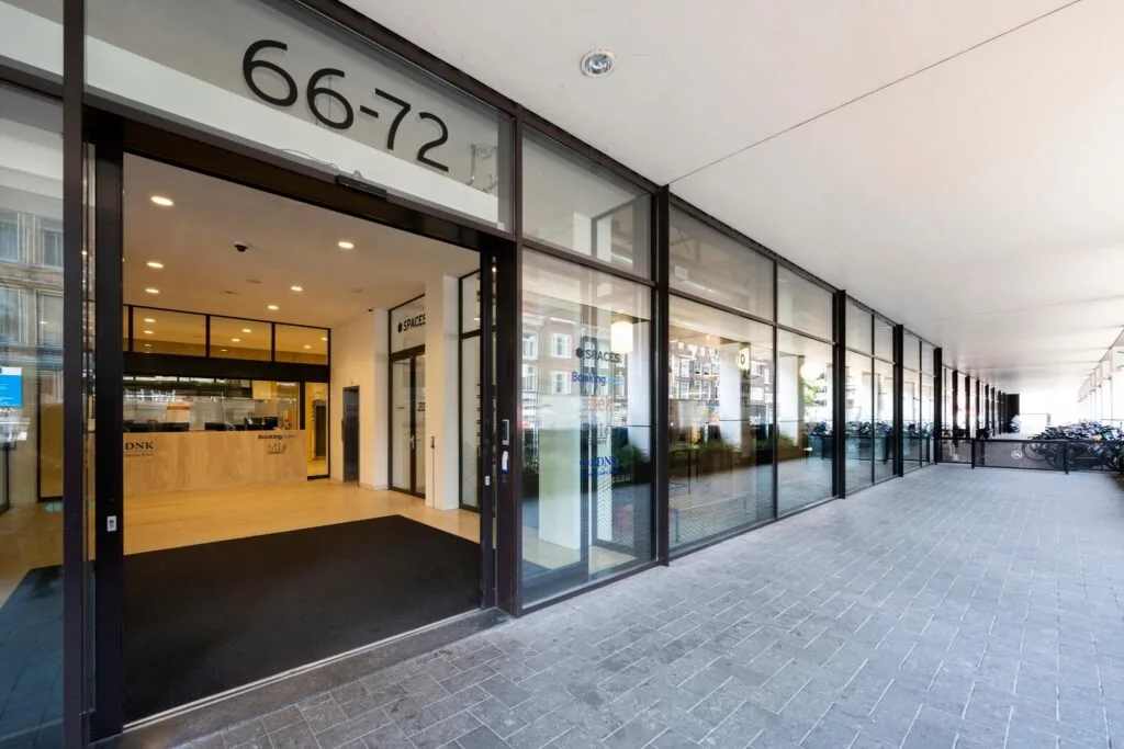 Entree van het kantoorgebouw aan de Vijzelstraat 66-72 met glazen gevel en zicht op de receptie van Spaces.