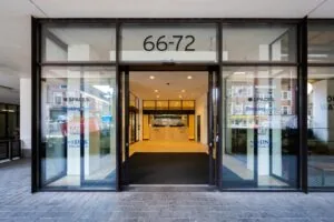 Glazen entree van het kantoorgebouw aan de Vijzelstraat 66-72 in Amsterdam met bedrijfsnamen op de ruiten.