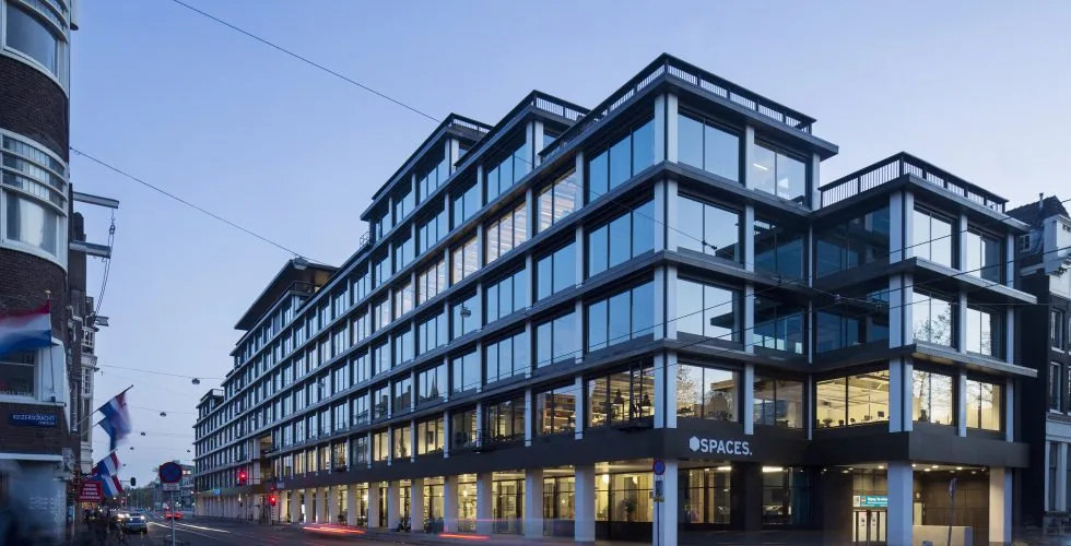 Modern kantoorgebouw van Spaces aan de Vijzelstraat in Amsterdam bij schemering.