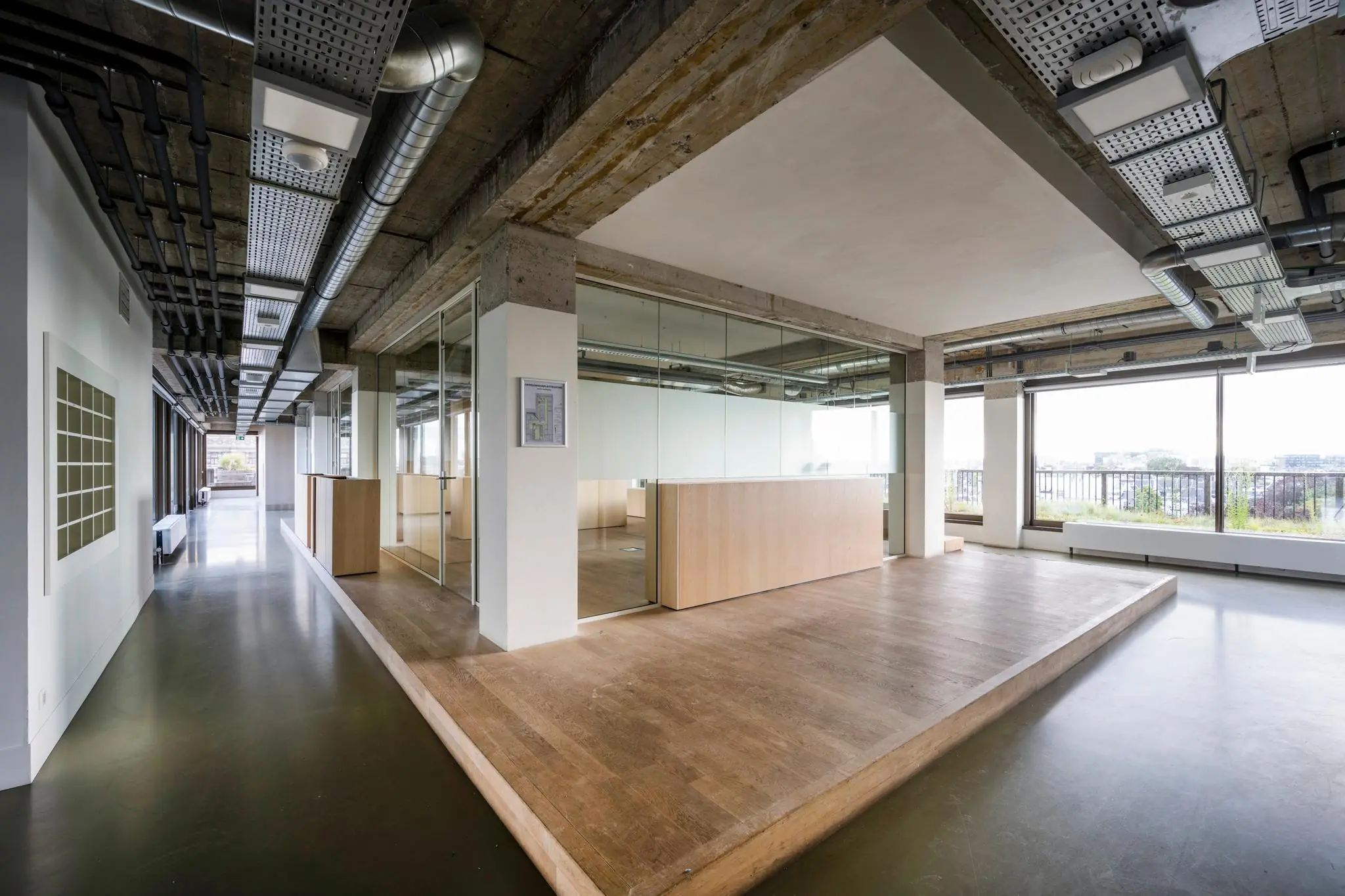 Moderne kantoorruimte aan de Vijzelstraat met glazen wanden, houten vloer en industrieel plafond.