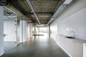 Modern industrieel kantoorinterieur aan de Vijzelstraat met een open ruimte, glazen wanden en een kitchenette.