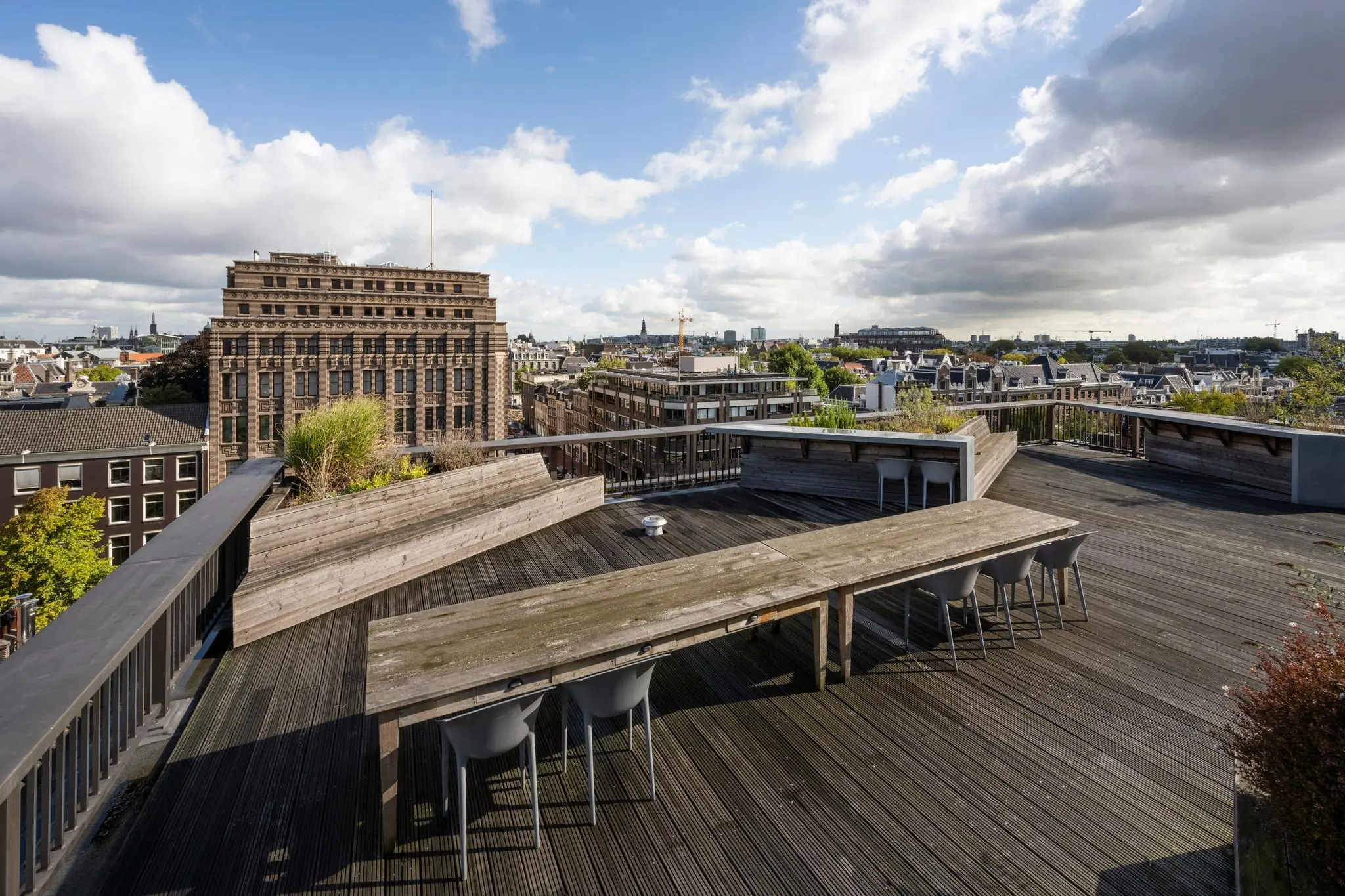 Dakterras met houten zitgedeelte en uitzicht op de Vijzelstraat en het centrum van Amsterdam.