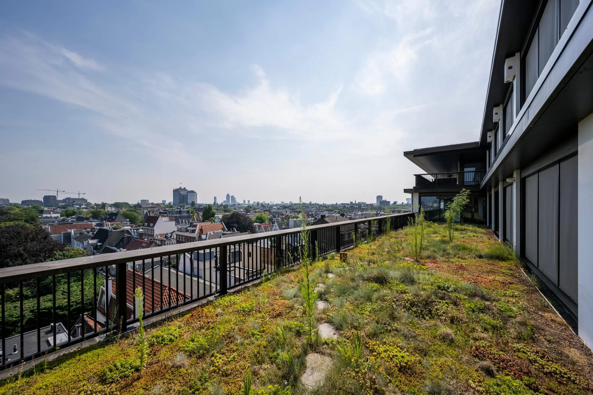 Groendak op een modern appartementencomplex aan de Vijzelstraat met uitzicht over de stad.