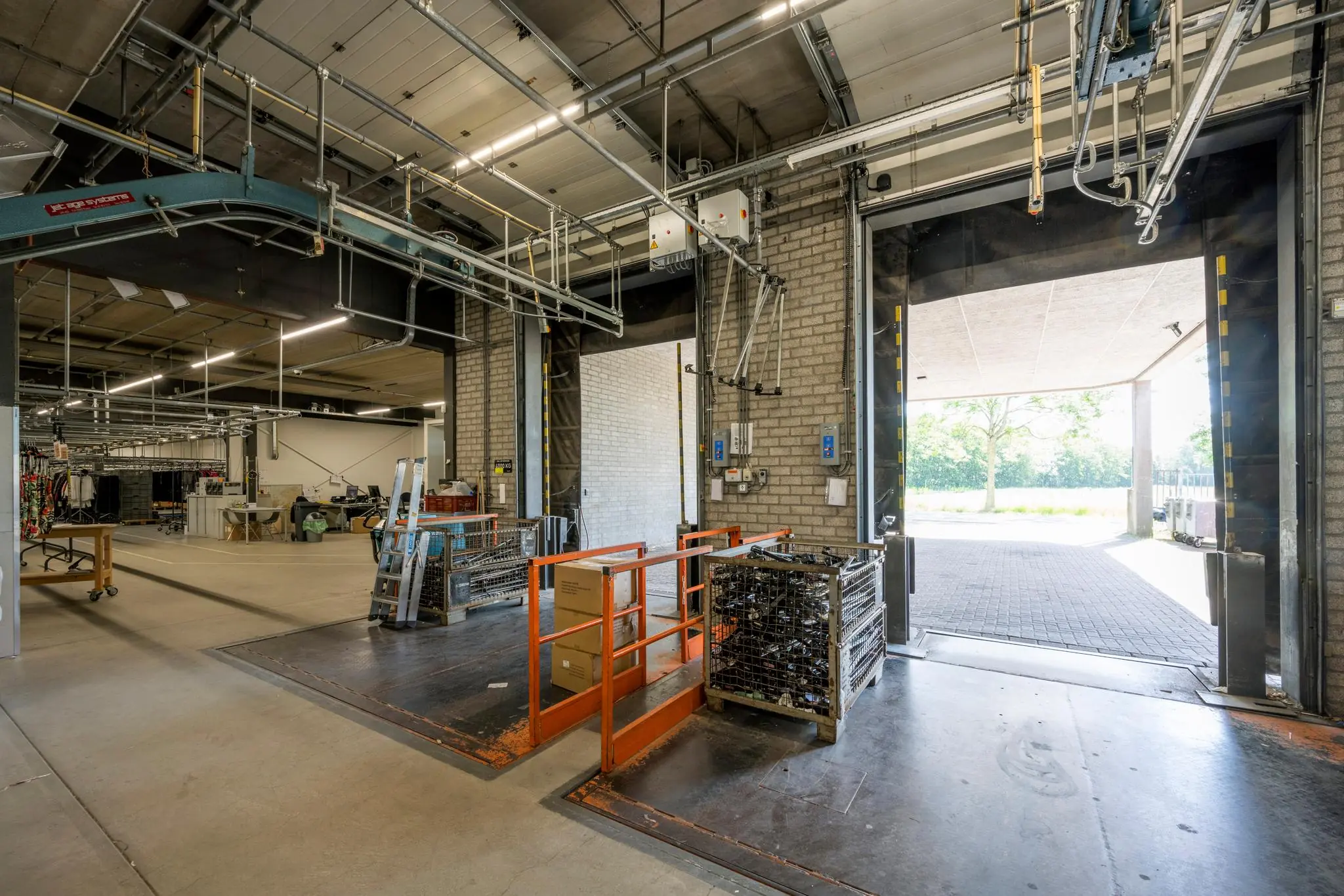 Logistieke laad- en losruimte in een industriële hal bij Stammerhove met open overheaddeuren en metalen opslagrekken.