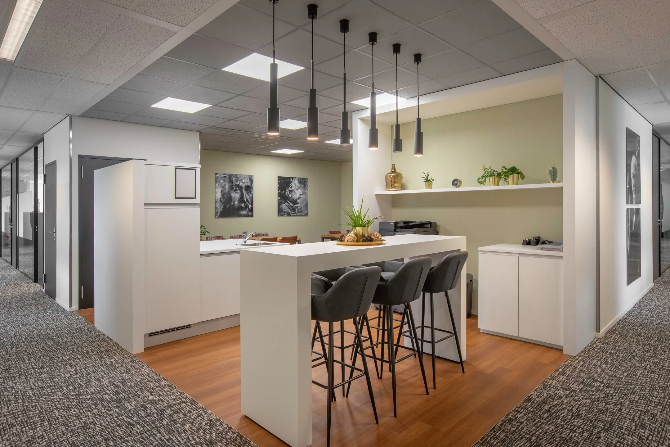 Een moderne kantoorruimte met een hoge tafel, zwarte barkrukken en decoratieve planten.