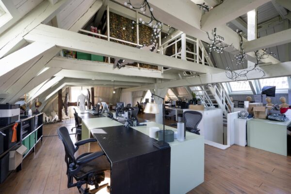 Modern kantoor in een sfeervolle zolderruimte aan de Leidsegracht met houten balken en designmeubilair.