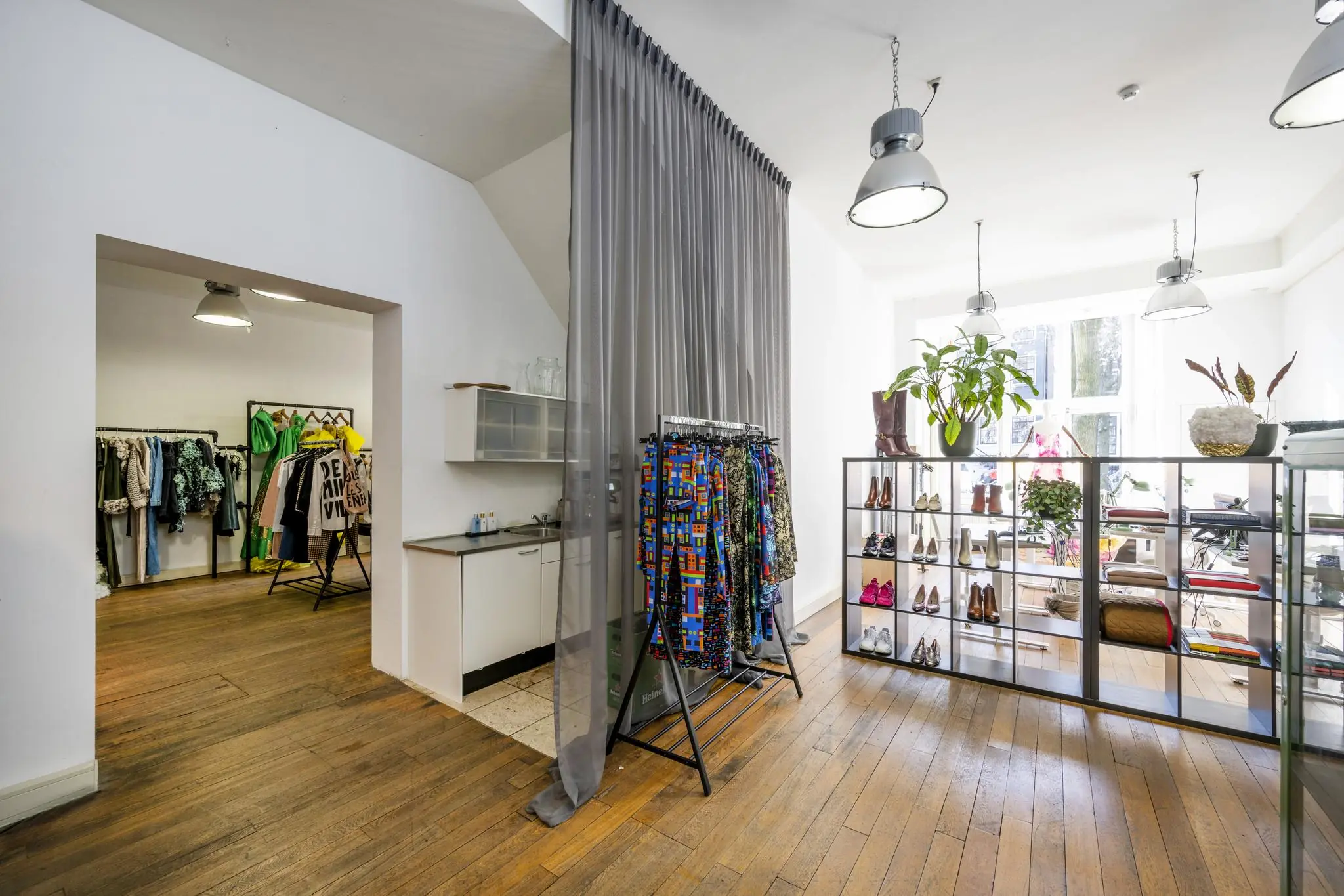 Licht en modern kledingwinkelinterieur aan de Leidsegracht met kledingrekken, schoenenrekken en grote ramen.