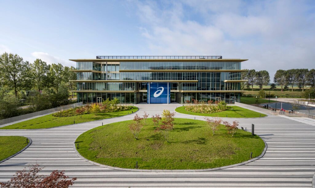 Modern kantoorgebouw van Asics aan de Taurusavenue met symmetrische tuin en glazen gevel.