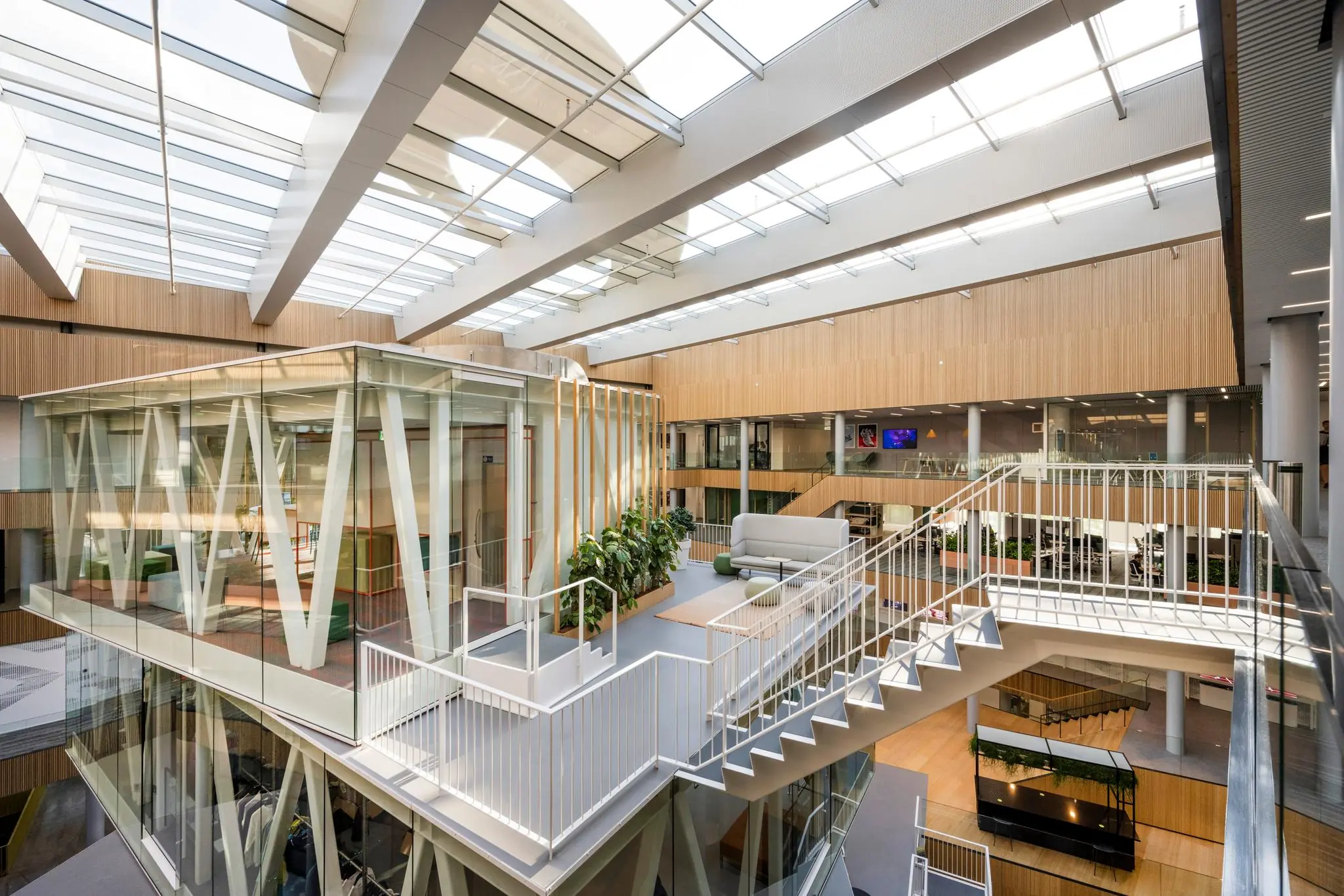 Licht en modern atrium van het kantoorgebouw Taurusavenue met glazen vergaderruimte, open trappen en zithoeken.