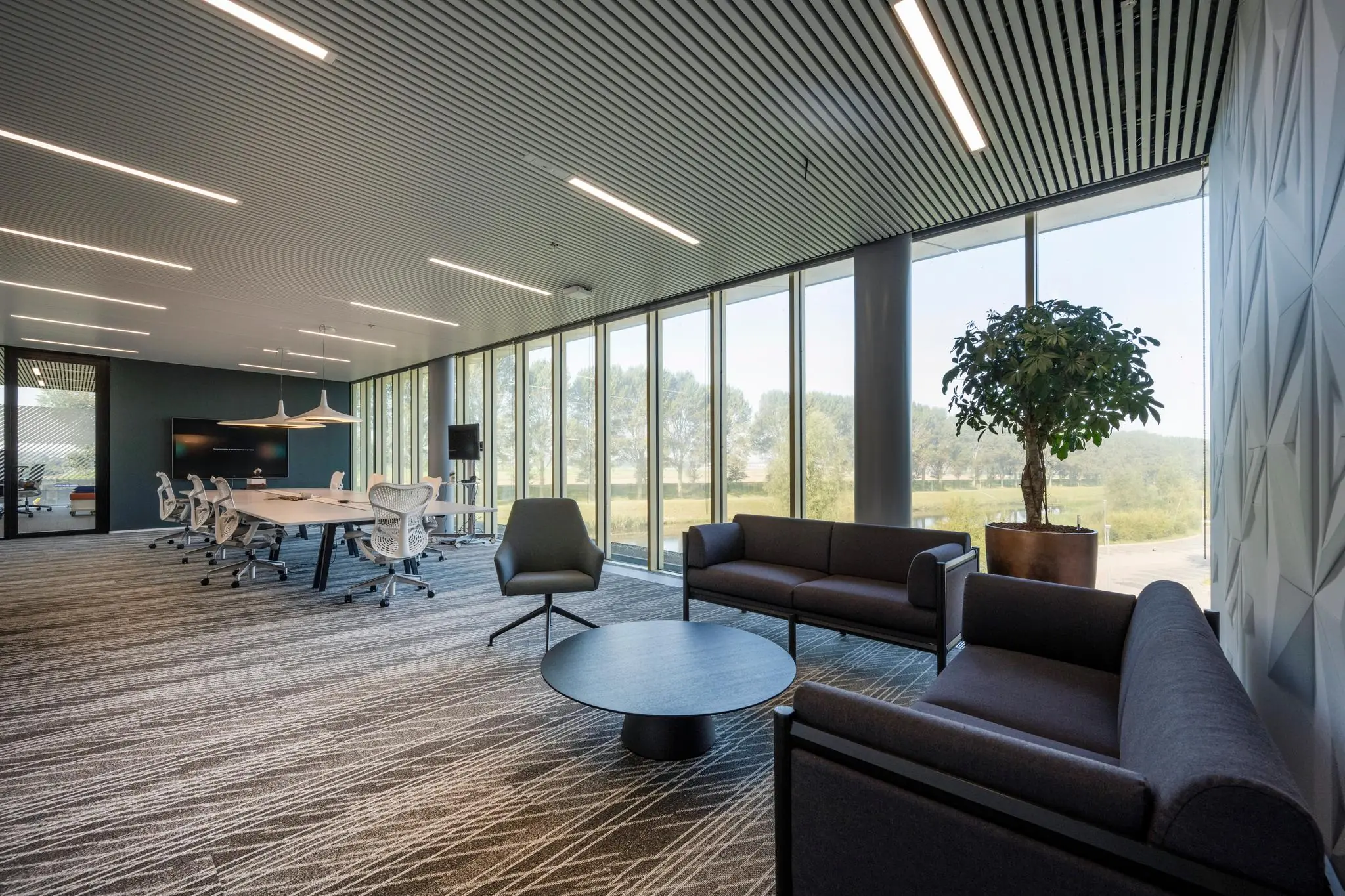 Moderne kantoorruimte aan Taurusavenue met vergadertafel, zithoek en grote raampartijen met uitzicht op groen landschap.