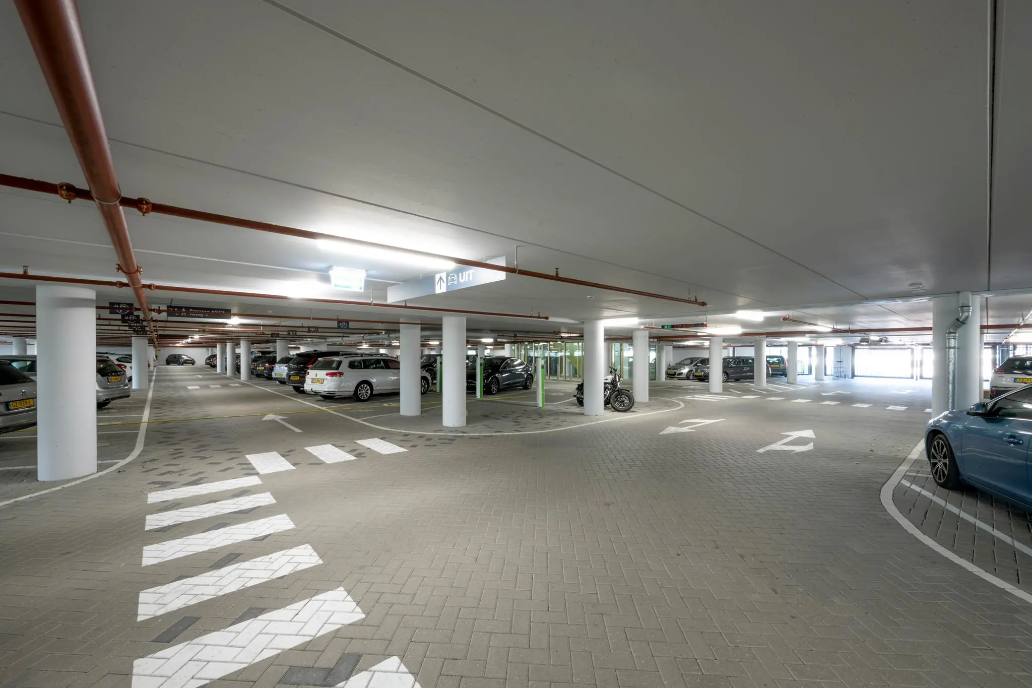Overzicht van een moderne, goed verlichte ondergrondse parkeergarage aan de Taurusavenue met geparkeerde auto's en duidelijke wegmarkeringen.
