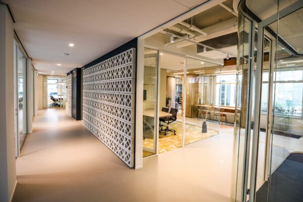 Moderne kantoorruimte met glazen vergaderruimtes en een gang met decoratieve wand.