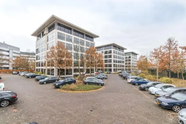 Zakelijk kantoorgebouw genaamd Marathon met omliggende parkeerplaatsen en herfstkleurige bomen.