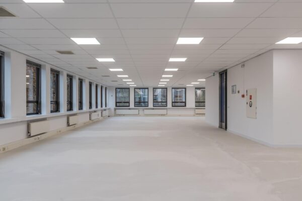 Lege, modern og verlichte kantoorruimte met grote ramen en systeemplafond.