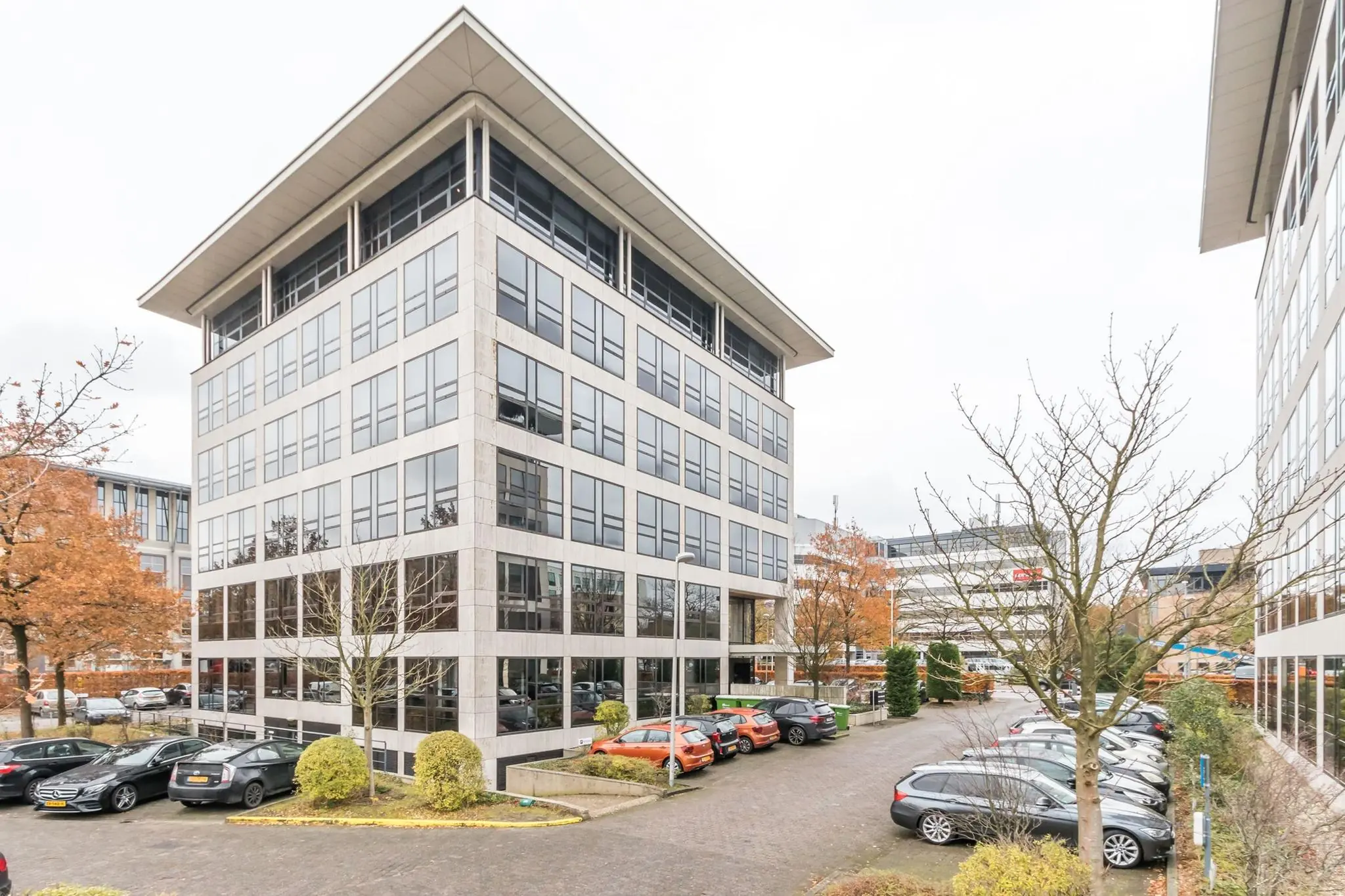 Modern kantoorgebouw aan de Marathon 5 in Amsterdam met parkeerplaatsen en omliggende kantoren.