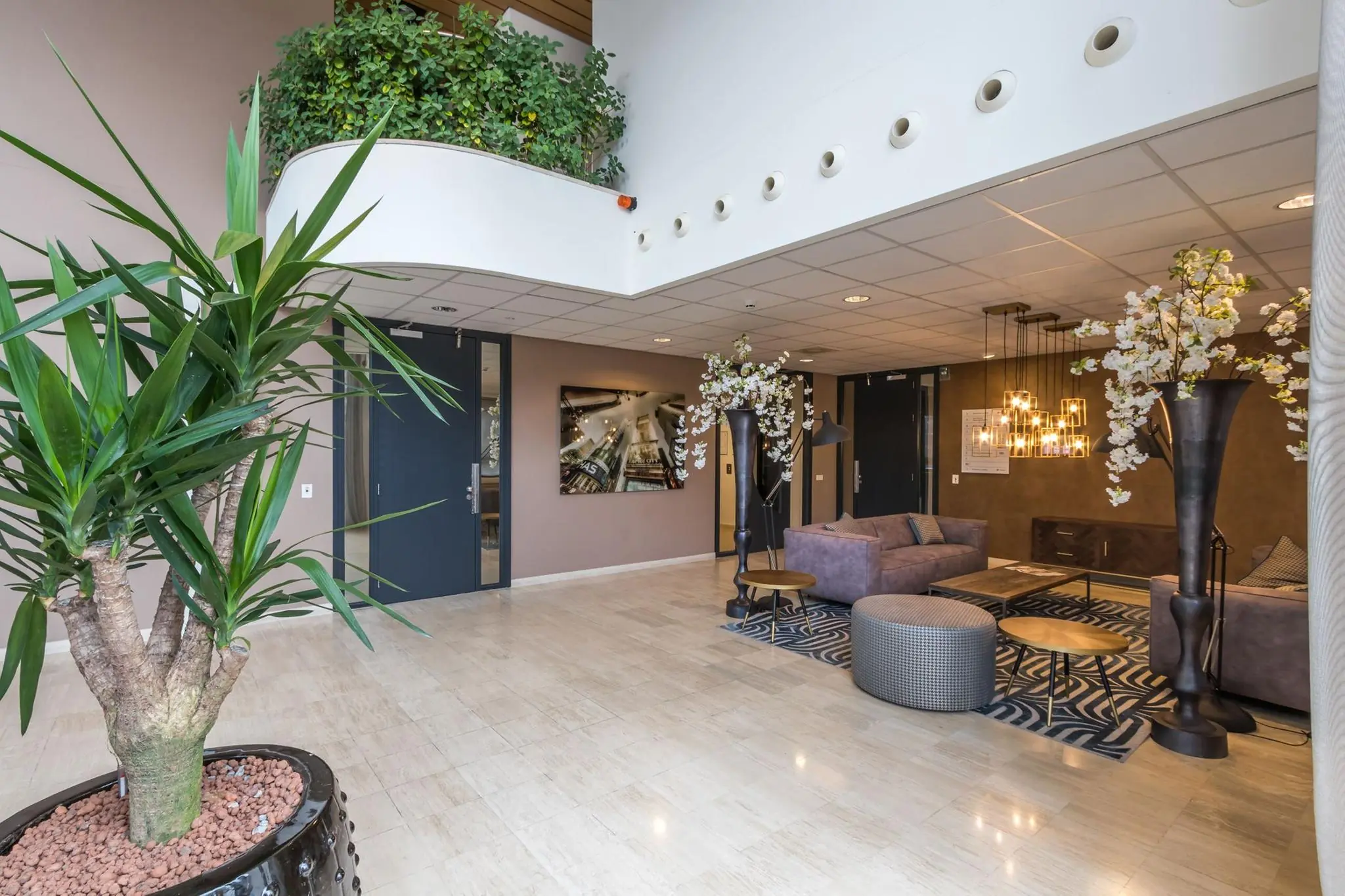 Moderne lobby met zitruimte, sfeerverlichting, sierplanten en kunst aan de muur in het gebouw Marathon.