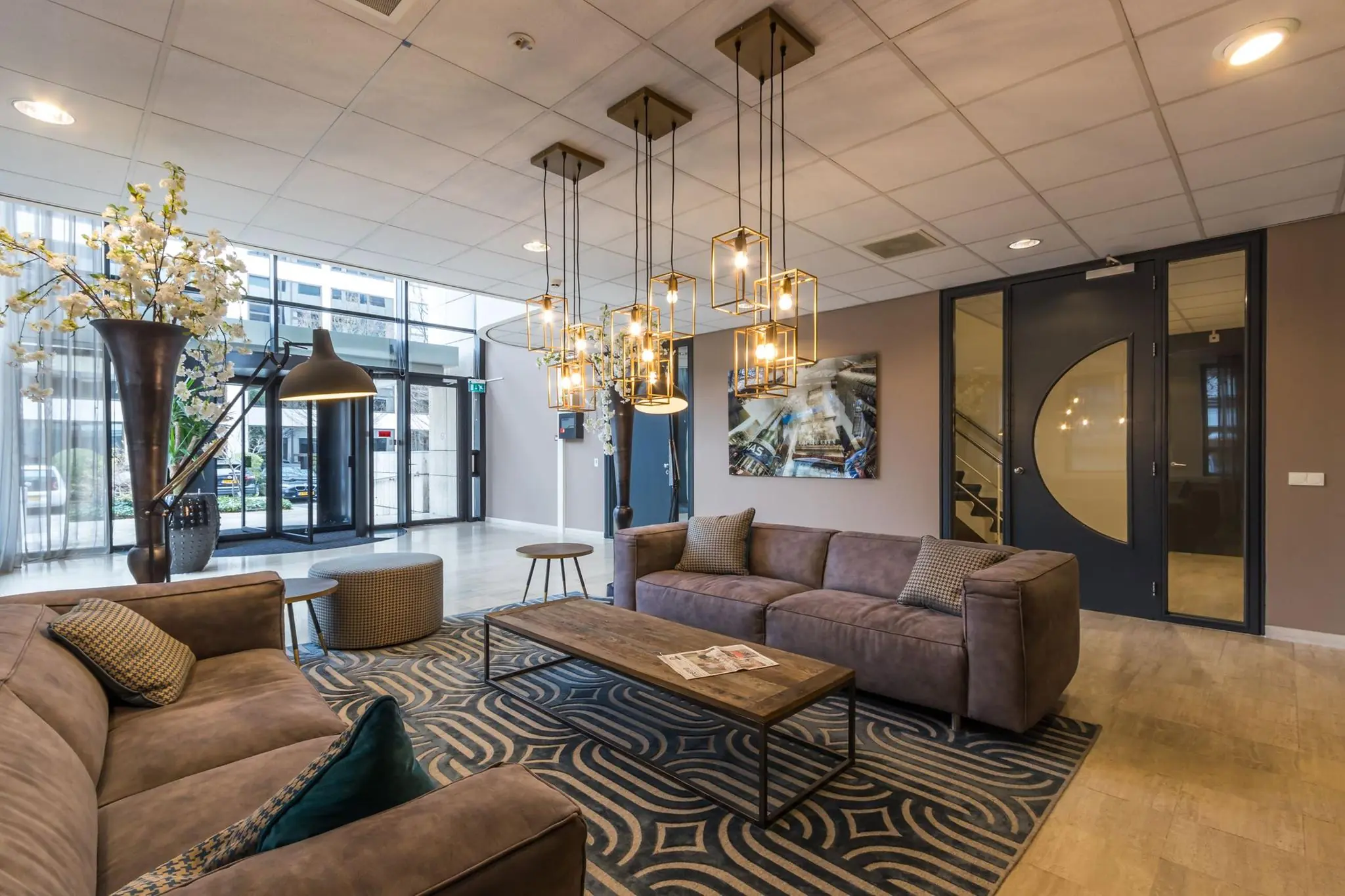 Moderne en sfeervol ingerichte lobby met zitgedeelte, designverlichting en grote raampartijen.