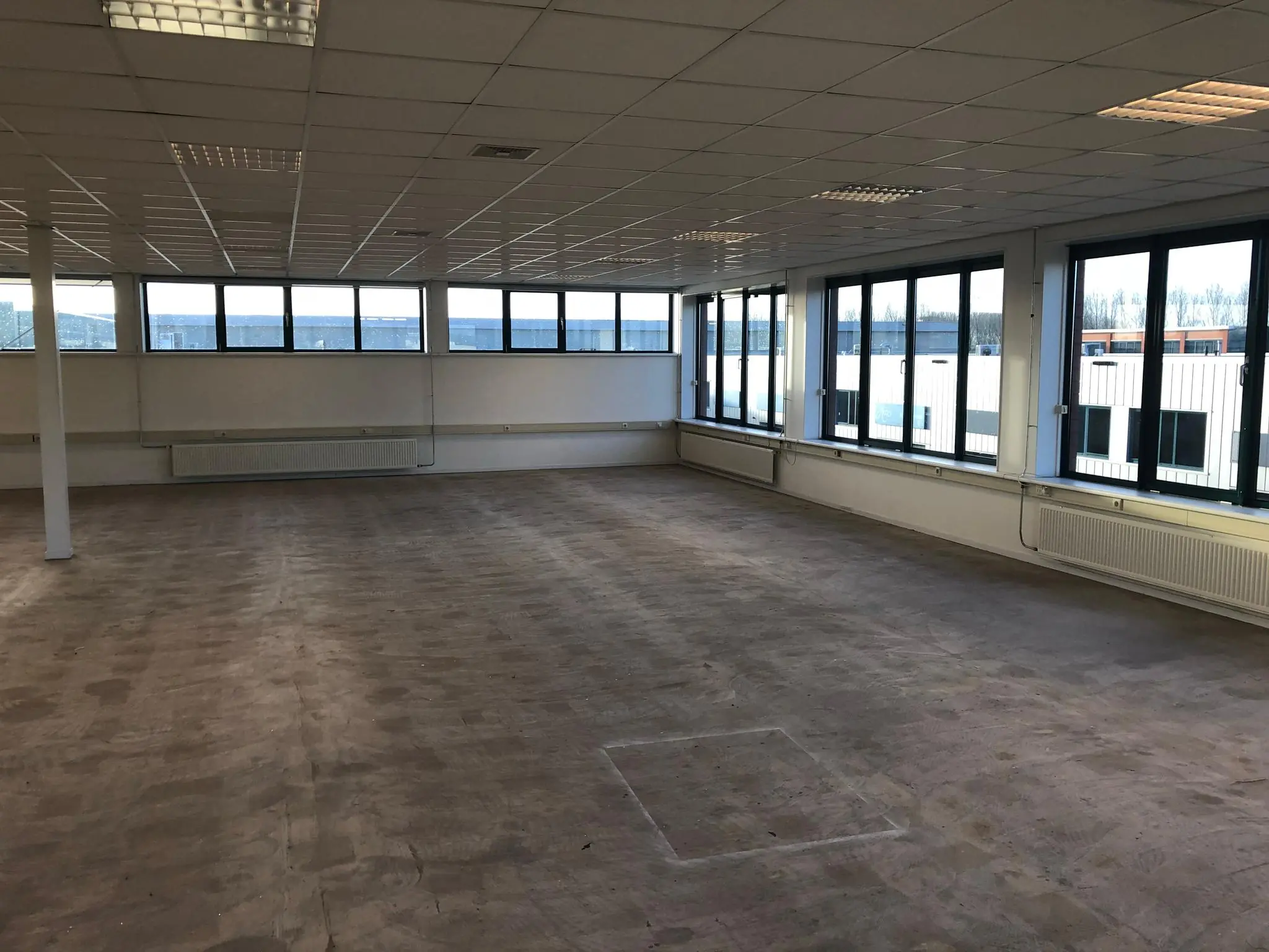 Lege kantoorruimte met systeemplafond en grote ramen aan de Sydneystraat.