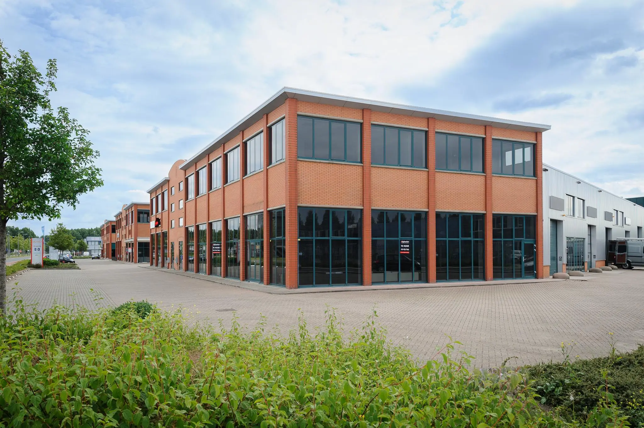 Modern rood bakstenen kantoorpand aan de Sydneystraat op een bedrijventerrein met ruime parkeergelegenheid.