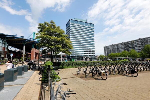 Fietsparkeerplaatsen op het Bogaardplein met op de achtergrond een hoog kantoorgebouw en winkelcentrum.