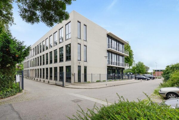 Modern kantoorgebouw aan de Rijksstraatweg met grote ramen en omheind terrein.