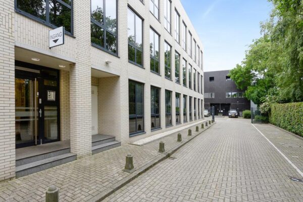 Vooraanzicht van een modern kantoorpand aan de Rijksstraatweg met entree en parkeerruimte.