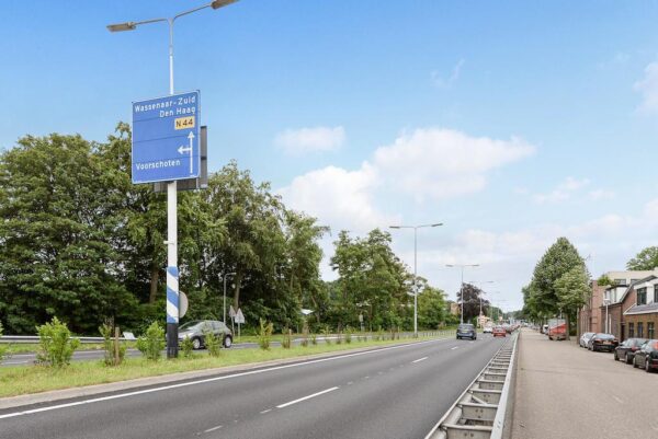 Drukke verkeersweg Rijksstraatweg met bewegwijzering naar Wassenaar-Zuid, Den Haag en Voorschoten.