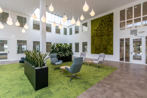 Moderne, lichte kantoorlobby aan de Volmerlaan met groene accenten, planten en loungezitjes.