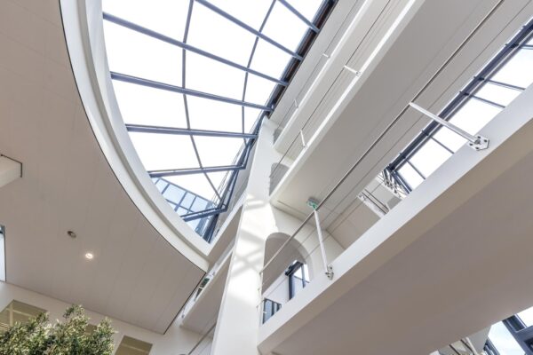 Modern atrium met glazen dak en meerdere etages in een kantoorpand aan de Volmerlaan.