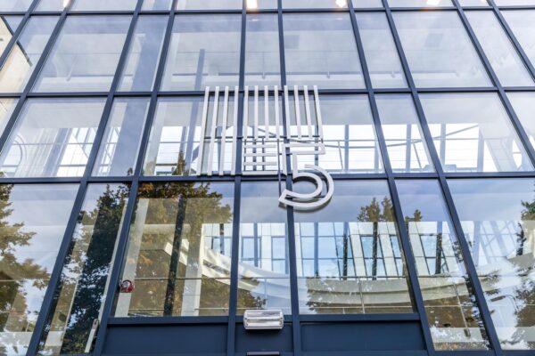Glazen gevel van een modern kantoorgebouw aan de Volmerlaan met groot nummer 5 op de voorzijde.