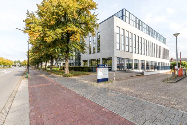 Modern kantoorpand aan de Volmerlaan 3-5 in een boomrijke straat met fietspad en parkeergelegenheid.