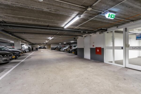 Ondergrondse parkeergarage aan de Volmerlaan met geparkeerde auto's en een nooduitgang.