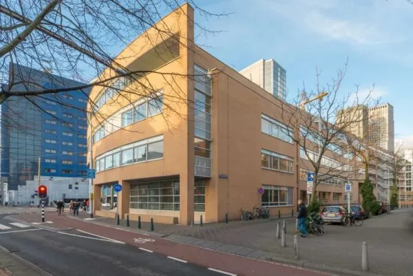 Straatbeeld van het Spui in Den Haag met een hoekpand van baksteen en omliggende hoogbouw.