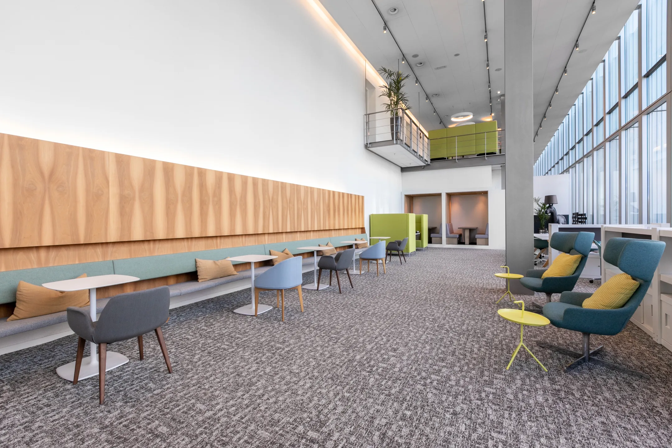 Een moderne, lichte kantoorruimte met zitgedeelte, tafels en stoelen en grote ramen.