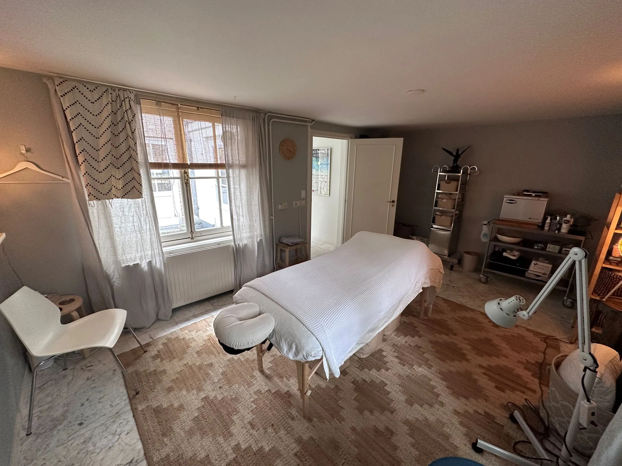 Behandelruimte met een massage- of behandeltafel in een rustgevende, sfeervol ingerichte kamer.