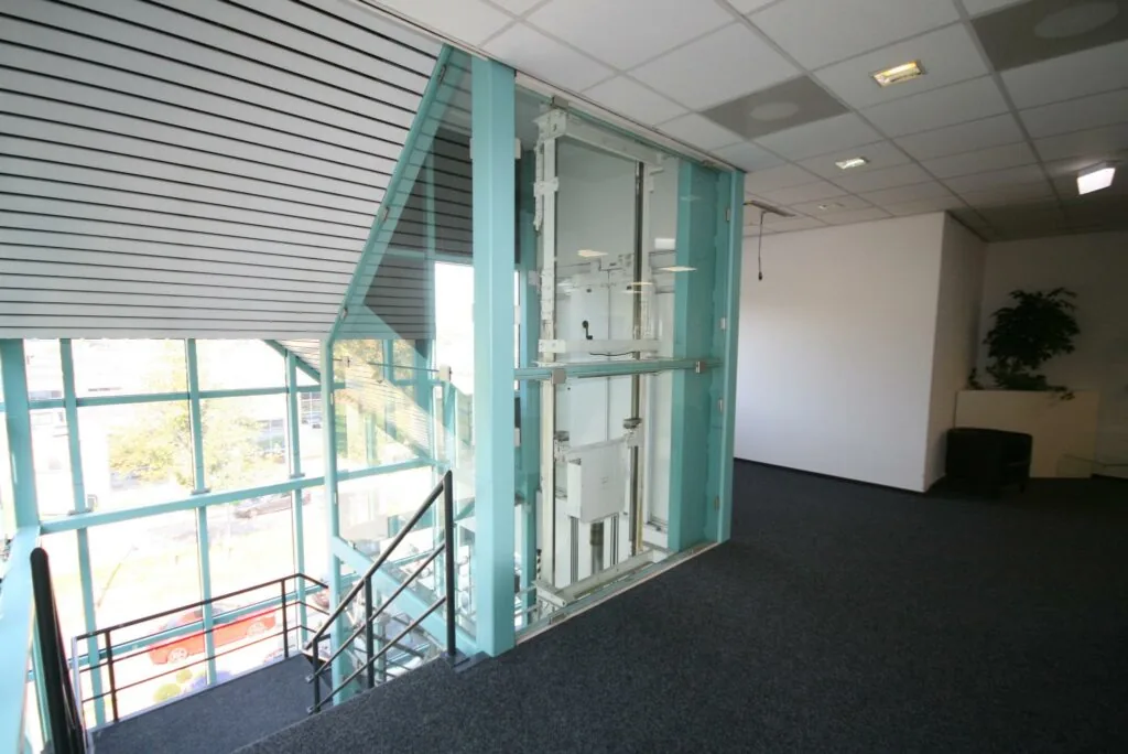 Moderne kantoorgang met een glazen lift en uitzicht op de Corkstraat.