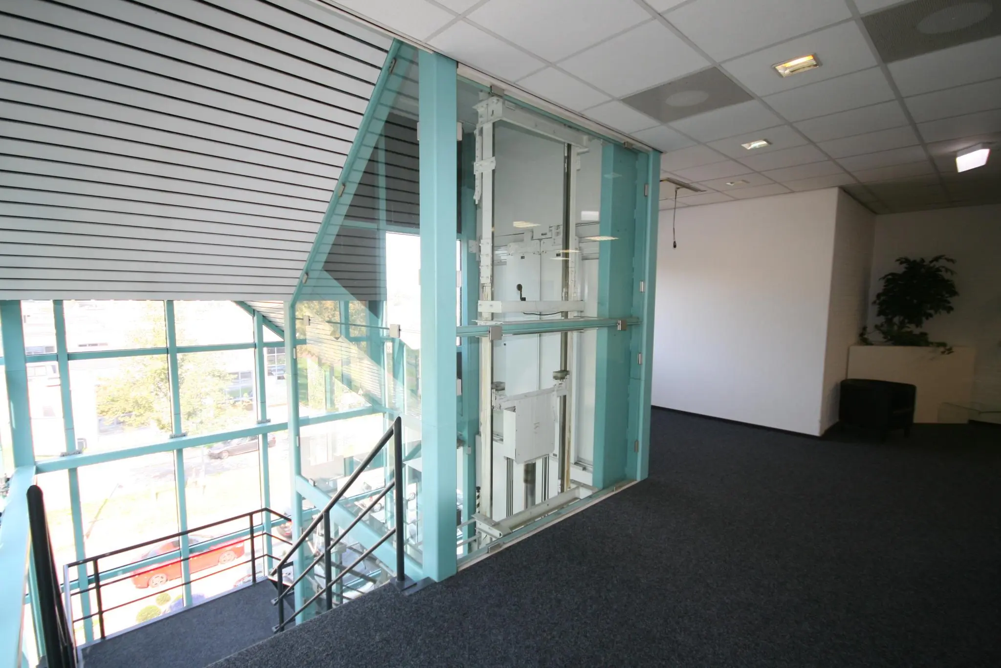 Moderne kantoorgang met een glazen lift en uitzicht op de Corkstraat.