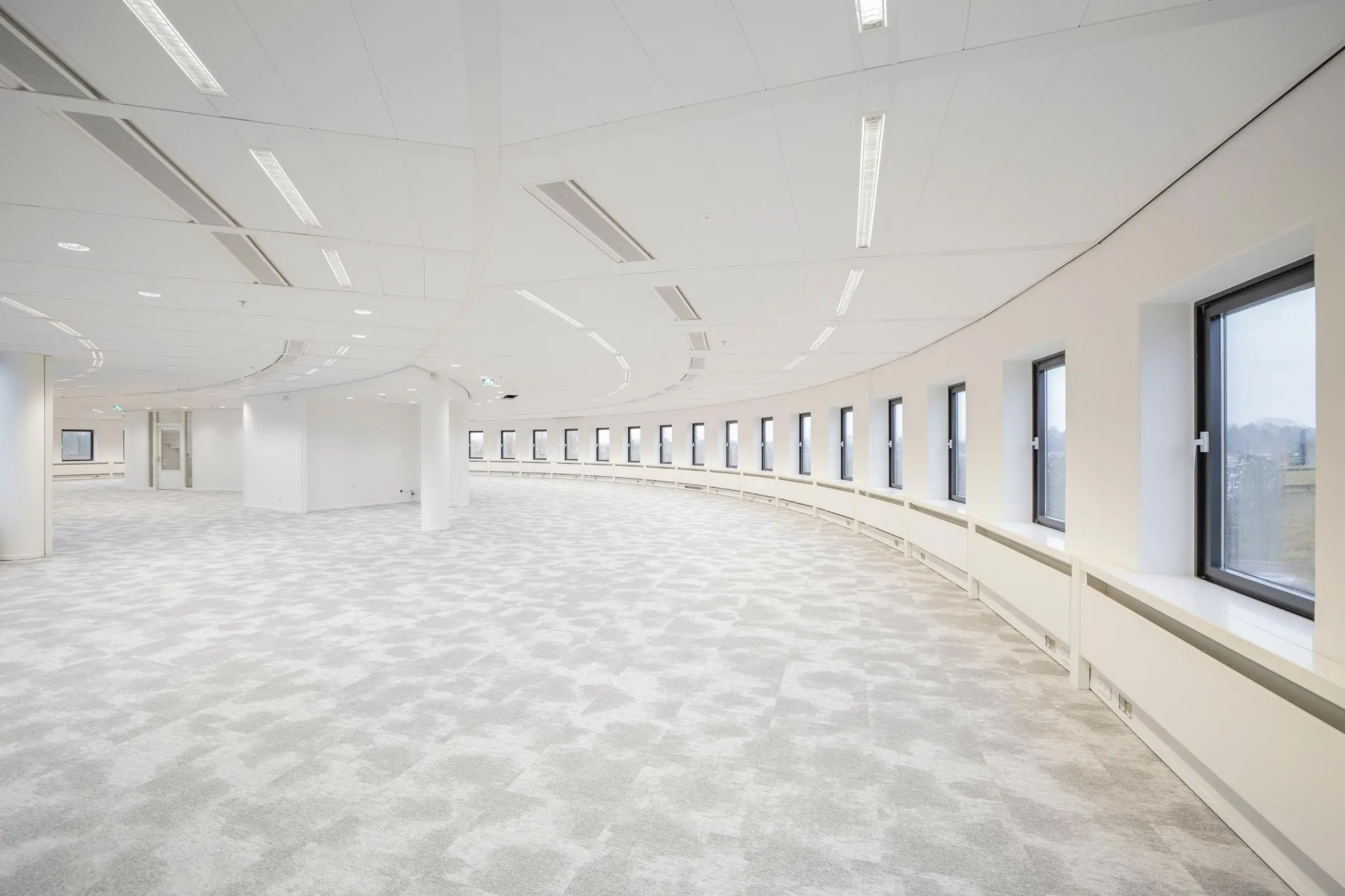 Licht, ruim en modern kantoorinterieur aan de Euclideslaan met gebogen raamwand en grijs tapijt.