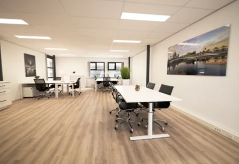 Modern kantoorinterieur aan de Arlandaweg met witte bureaus, zwarte stoelen en houten vloer.